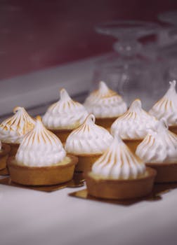 A delectable array of lemon meringue tarts with golden peaks, perfect for gourmet dessert lovers.
