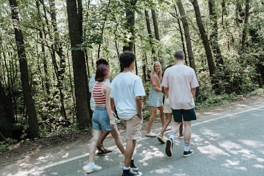 Group of teenagers walking together on a forest pathway, enjoying outdoor nature.