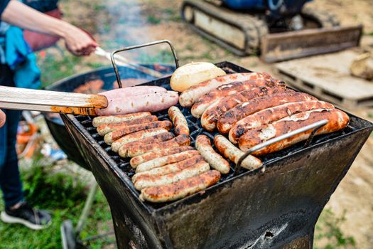Grilling an assortment of sausages and bread at an outdoor barbecue on a sunny day.